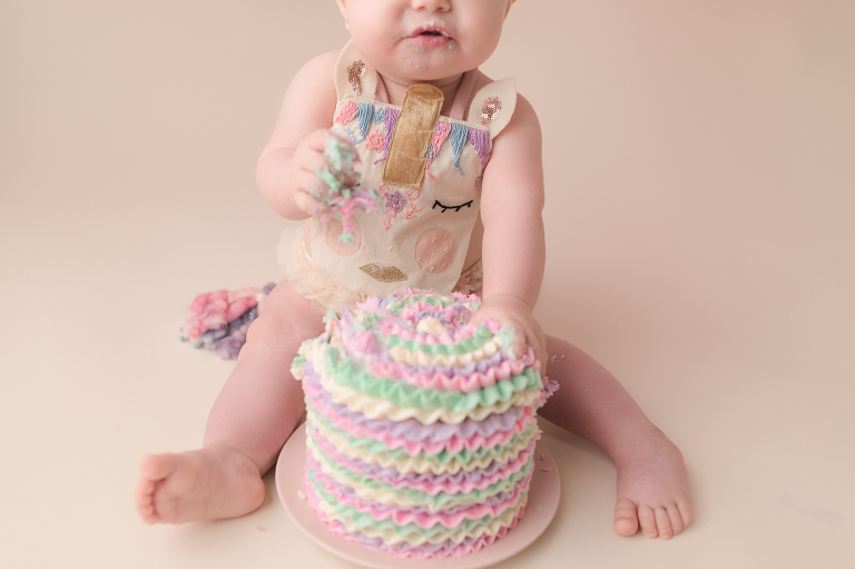 one year old baby girl grabbing smash cake